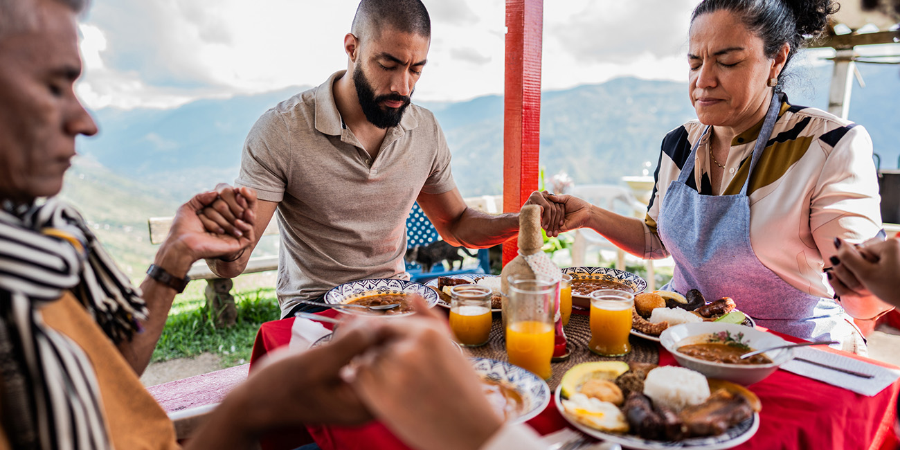 Family holding hands at dinner table