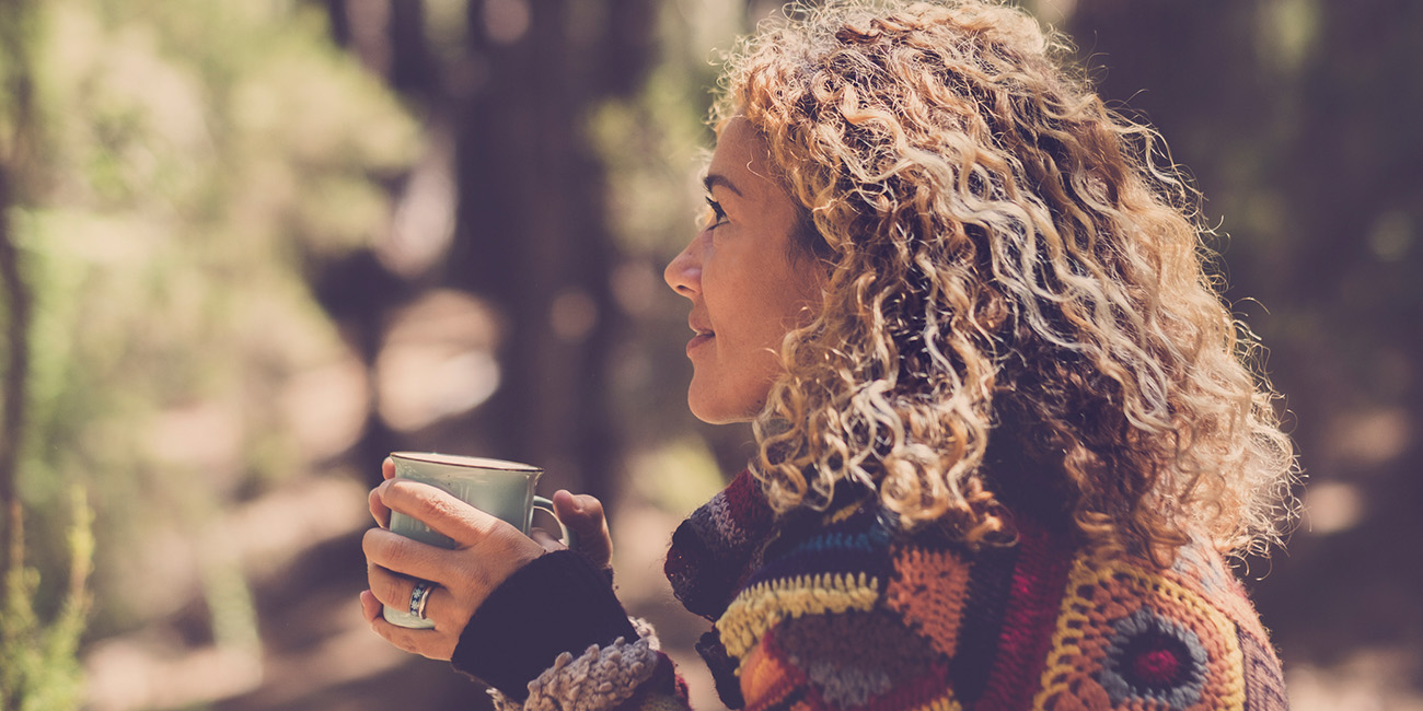 Woman camping drinking a cup of coffee